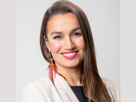 ORCC Executive Director, Candice Shaw. light tan colour skin, long straight brown hair, wearing red beaded earrings, and a cream colour blazer over a black top
